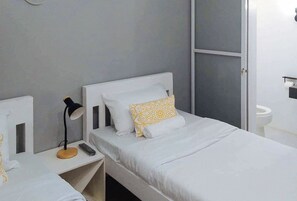 A small, neatly arranged bedroom with a single bed, a bedside table with a lamp, and a mirror. - Angels Bed And Breakfast Sipalay City By Reddoorz (Sipalay)
