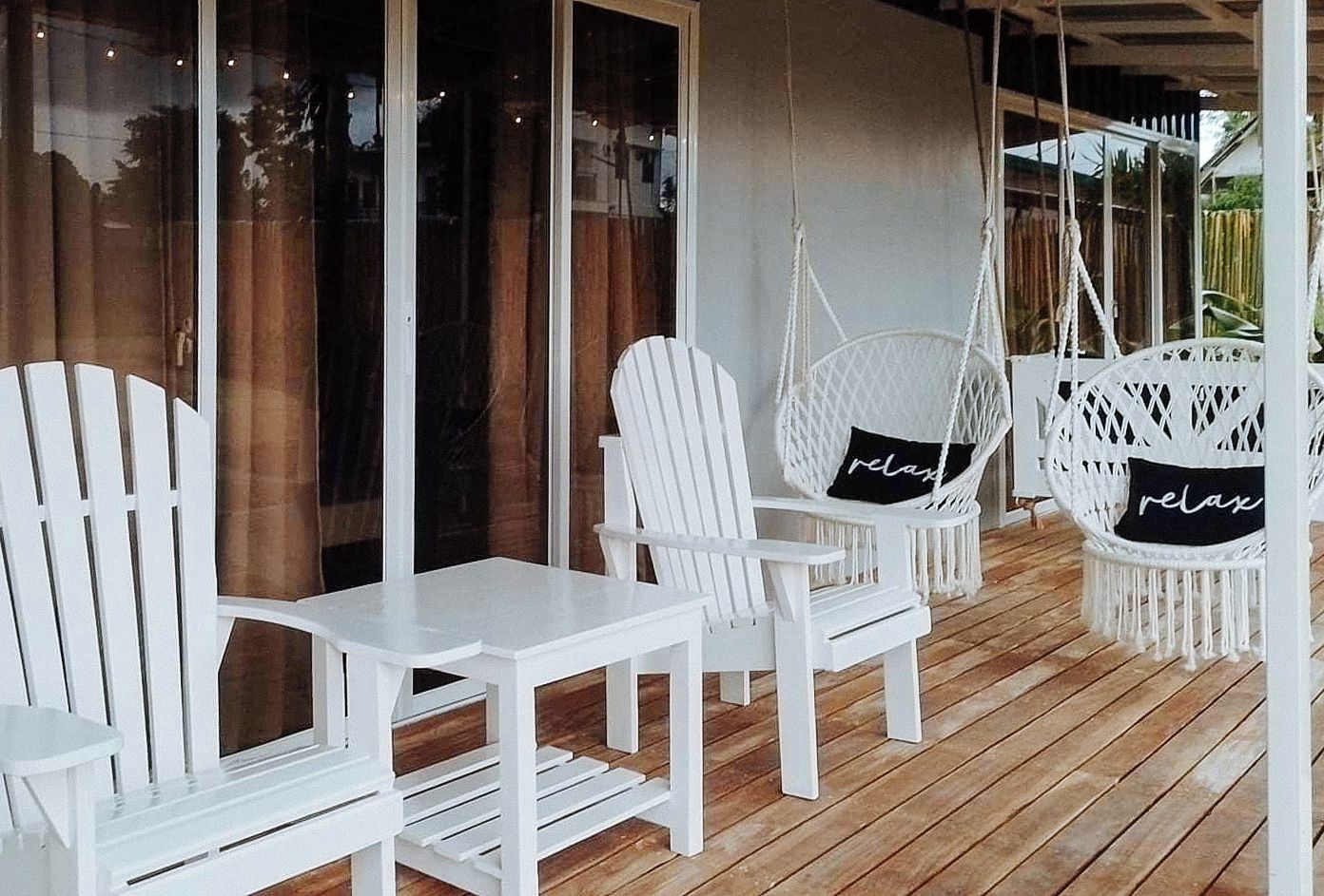 A wooden deck with white furniture, including chairs and a table.