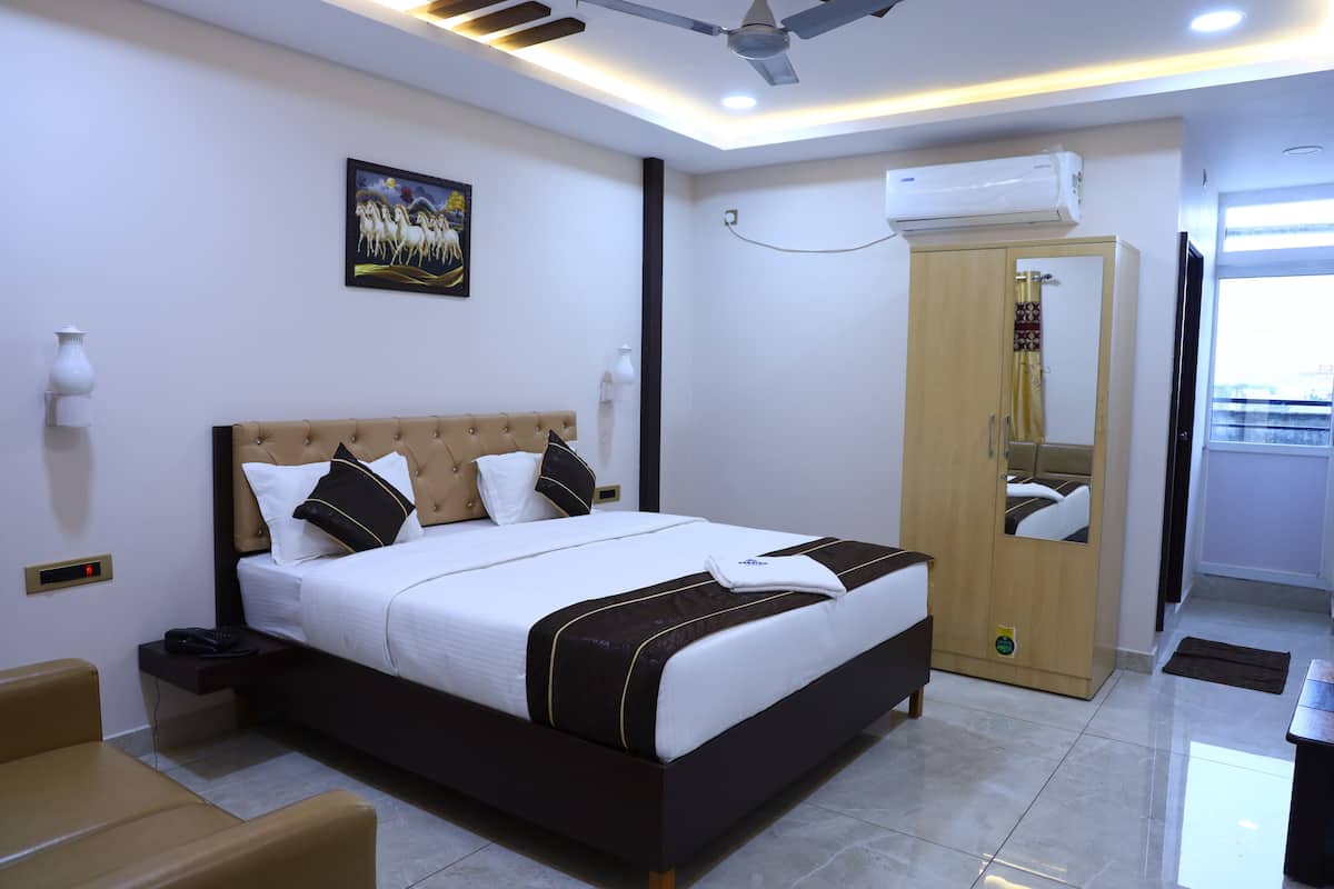 Quarto de hotel moderno com uma cama grande, um guarda-roupa, um ventilador de teto e um quadro na parede.