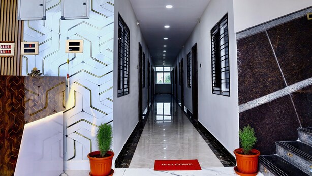 A modern hotel lobby with a long corridor, a reception desk, and potted plants.