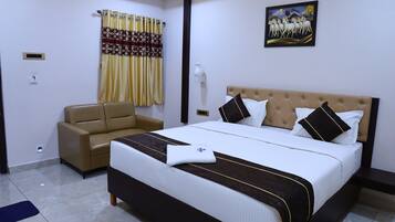 A hotel room with a large bed, a sofa, a painting on the wall, and a window with curtains.