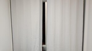 A hotel room with a bed, a window with curtains, and a towel on the bed. - Ideal Apartamento em Curitiba (Curitiba)