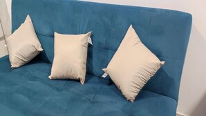 A teal sofa with three beige cushions. - Ideal Apartamento em Curitiba (Curitiba)