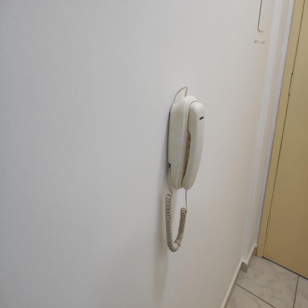 Un teléfono blanco sujeto a la pared en un pasillo.