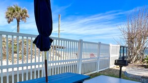 A blue picnic table with a white fence in the background.