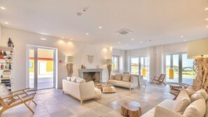 A spacious living room with a fireplace, sofas, and a view of the outdoors. - Resort Rural Quinta do Carrascal (Rio Maior)