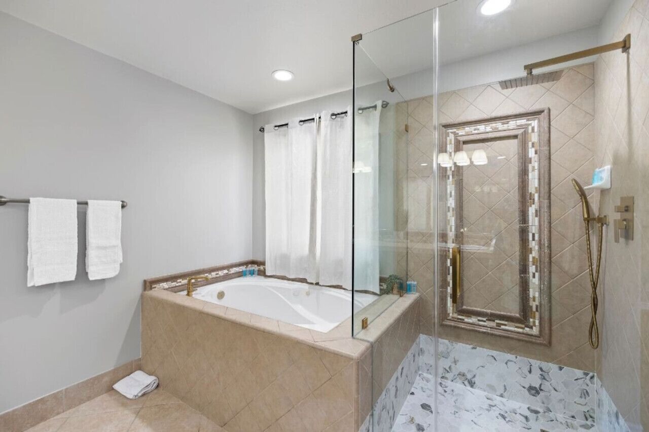 A modern bathroom with a freestanding bathtub, a glass-enclosed shower, and a marble-tiled floor.