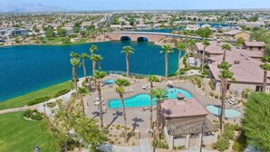 A residential area with a large body of water, a bridge, and a pool area with palm trees. - Desert Oasis in Palm Springs/Indio, California (Indio)