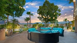 A patio area with a curved outdoor seating arrangement, string lights, and a view of the landscape. - Desert Oasis in Palm Springs/Indio, California (Indio)