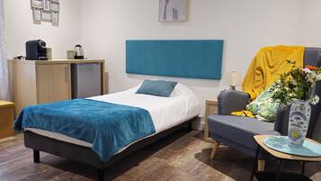 Een moderne slaapkamer met een bed, een bank, een koffiezetapparaat en een vaas met bloemen.