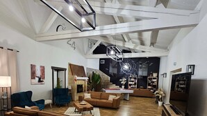 A spacious living room with a fireplace, wooden flooring, and a modern ceiling design.