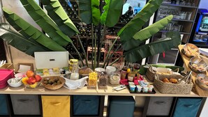 A breakfast bar with various food items, a laptop, and storage bins.