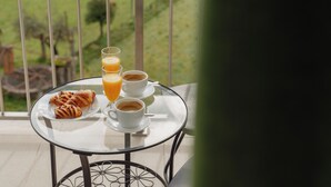 A table with croissants, orange juice, and coffee on a balcony with a view of a green landscape. - Bed and Breakfast Equitare Rural  (Miranda do Corvo)