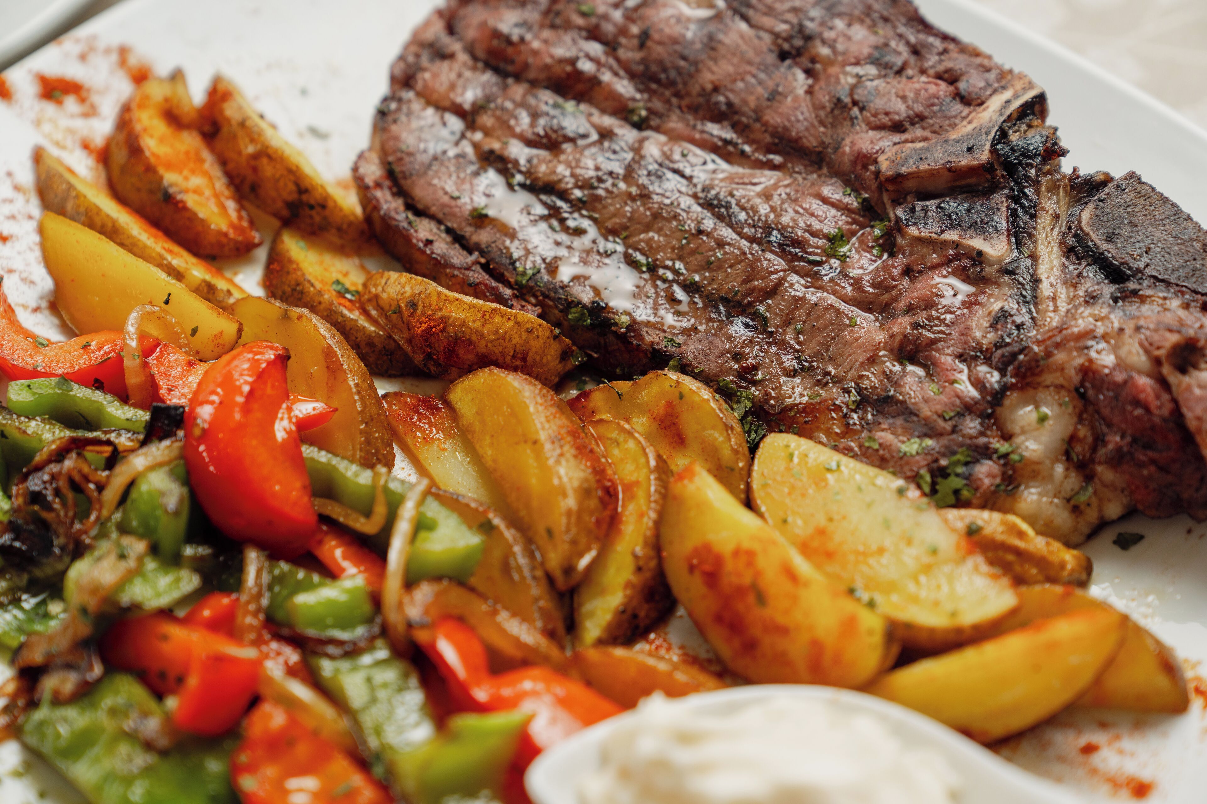 A plate with a steak, roasted potatoes, and grilled vegetables.