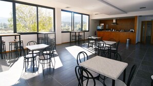 A spacious dining area with large windows, a kitchen area, and a view of the outdoors. - Bed and Breakfast Equitare Rural  (Miranda do Corvo)