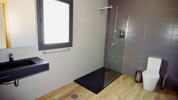 A modern bathroom with a glass-enclosed shower, a black sink, and a toilet.