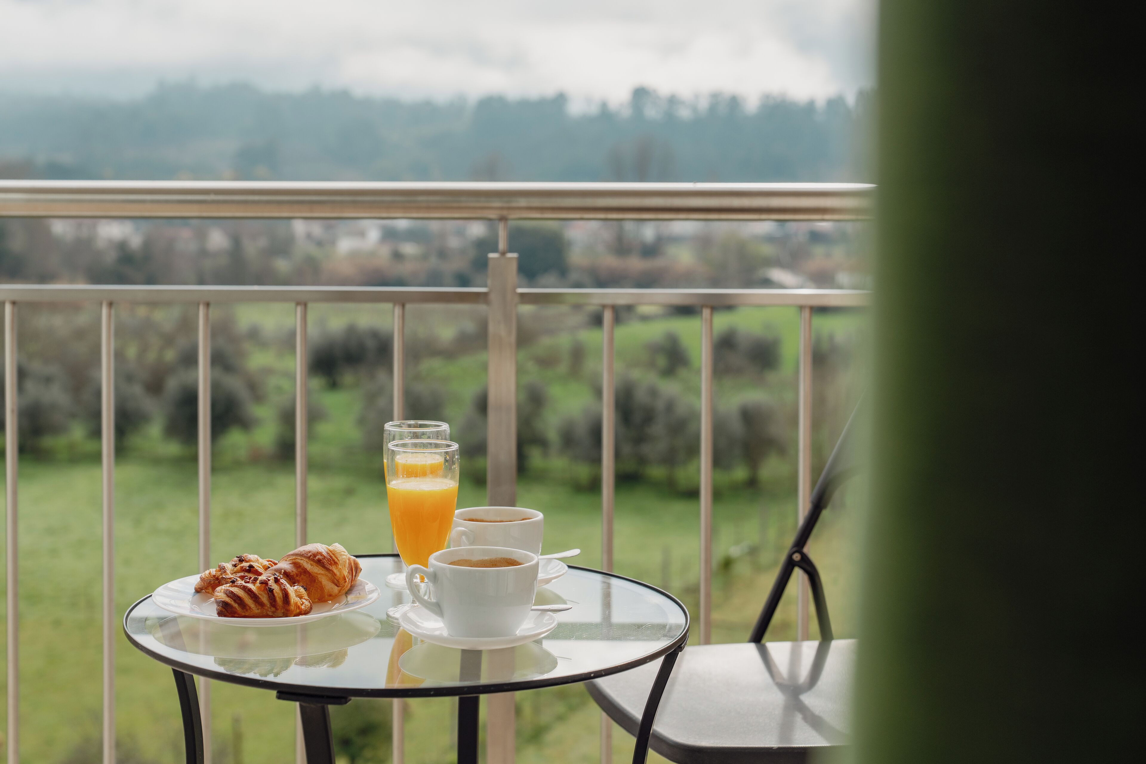 Un balcó amb una taula preparada per esmorzar, incloent croissants, cafè i suc d'aranja.