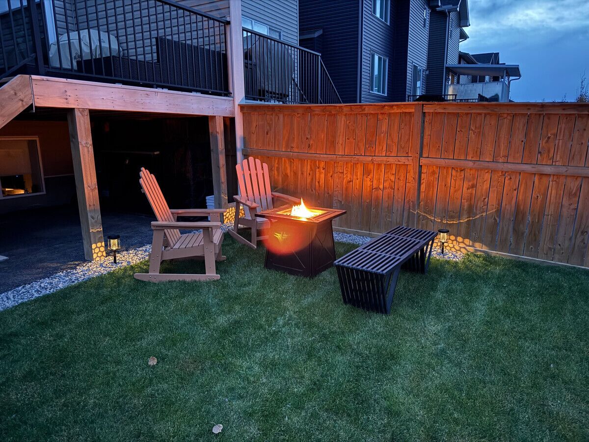 Ein Garten mit Feuerstelle, Holzstuhl und Bank.