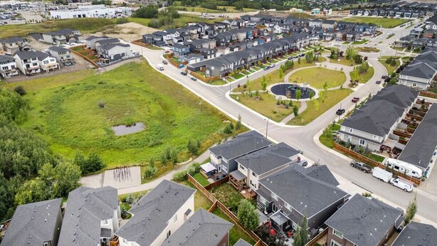 A residential area with houses, a green park, and a road. - Southern Horizons | Mini Nordic Spa | Fenced Yard (Cochrane)