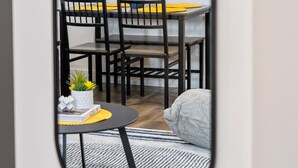 A modern dining area with a round wall clock, black chairs, a yellow table, and a small plant. - Southern Horizons | Mini Nordic Spa | Fenced Yard (Cochrane)