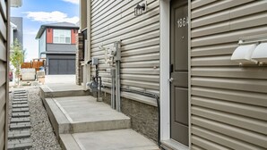 A residential building with a garage, a small front porch, and a door marked with the number 186A. - Southern Horizons | Mini Nordic Spa | Fenced Yard (Cochrane)