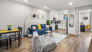A modern apartment with a living room, dining area, and kitchen. - Southern Horizons | Mini Nordic Spa | Fenced Yard (Cochrane)
