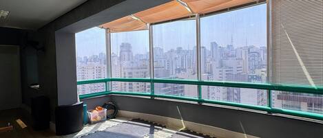 A room with large windows, a view of a cityscape, and tatami mats on the floor.