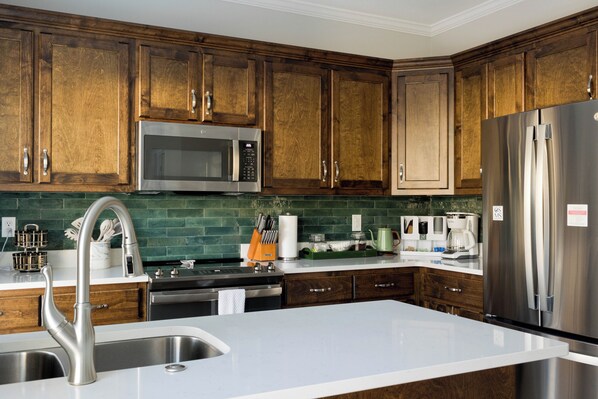 A modern kitchen with wooden cabinets, stainless steel appliances, and a white countertop.