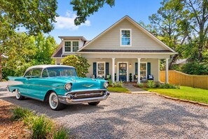 A classic turquoise Chevrolet car parked in front of a two-story house with a front porch and a number 614 sign.