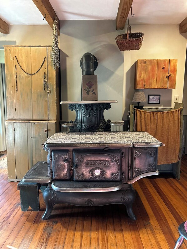 A vintage stove with ornate details and a wooden cabinet in the background. - Charming 3-bedroom farmhouse in welcoming Skaneateles, short walk to village. (Skaneateles)