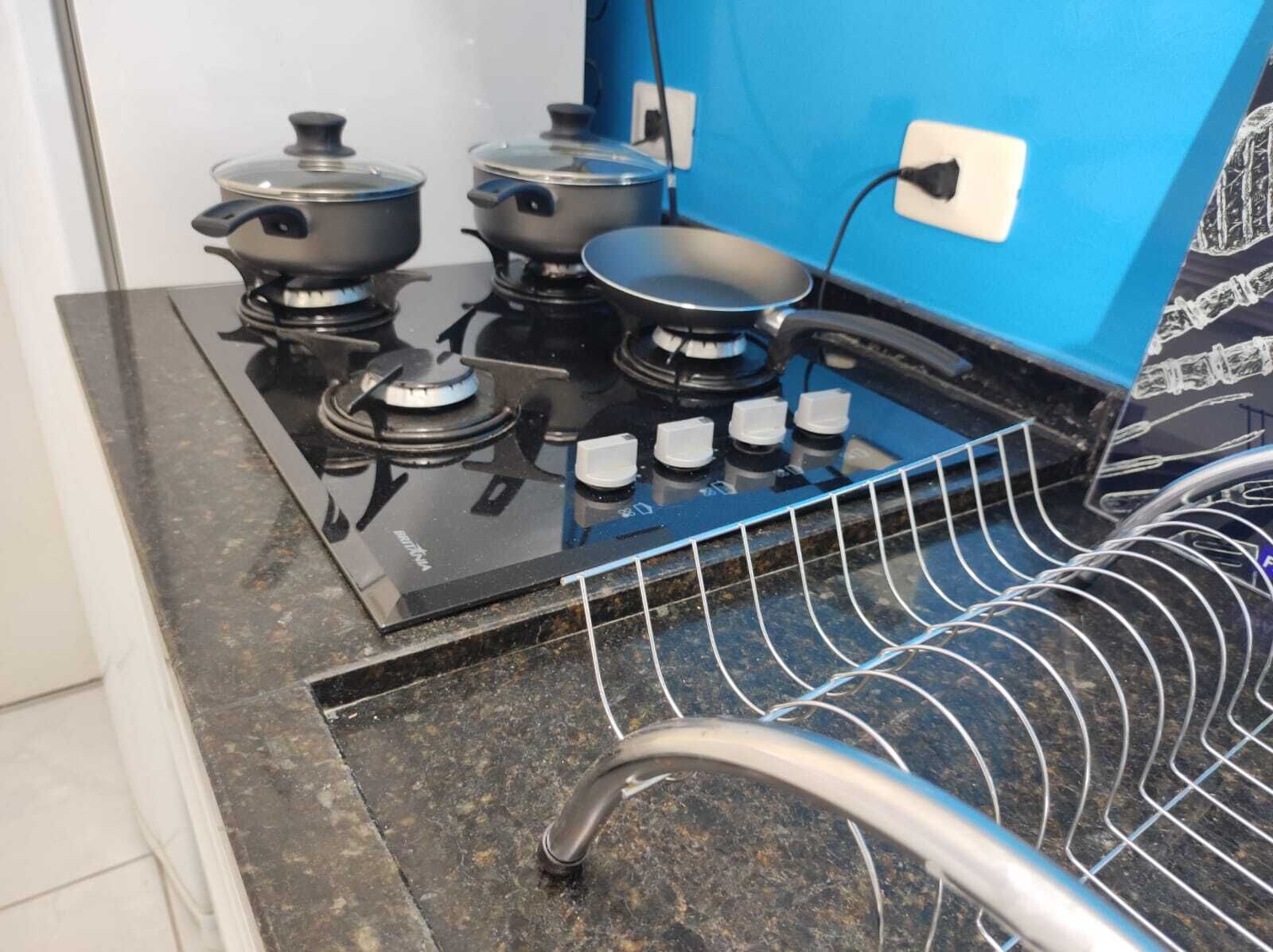 Una cocina con una estufa negra, tres ollas y una rejilla de alambre.