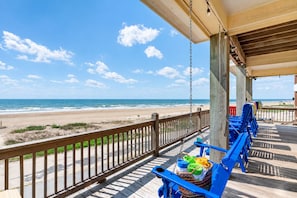 A wooden deck with a view of the beach and ocean.