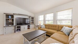 A living room with a large flat-screen TV, a beige sofa, and a coffee table. - Pool - 3 bedrooms - 2 baths - Pet Friendly - 3 Miles to Beach (Bonita Springs)