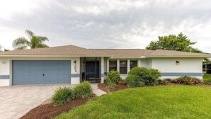 A single-story house with a garage, a covered porch, and a well-maintained lawn. - Pool - 3 bedrooms - 2 baths - Pet Friendly - 3 Miles to Beach (Bonita Springs)