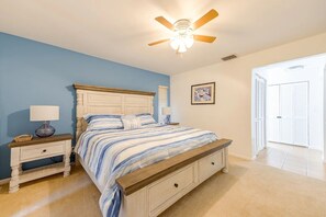A bedroom with a bed, nightstands, a ceiling fan, a framed picture, and a door. - Pool - 3 bedrooms - 2 baths - Pet Friendly - 3 Miles to Beach (Bonita Springs)