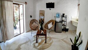 A room with a rustic ceiling, two wicker chairs, a small table, a water dispenser, and a sink. - Art-San Hotel (Isla Holbox)