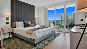 A modern bedroom with a large bed, a view of the city, and a balcony. - Find Tranquility in the Grove (Miami)