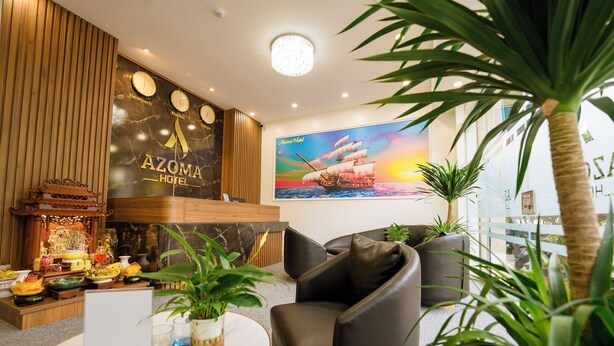 A lobby with a reception desk, seating area, and a large ship painting. - Azoma Hotel (Hanoi)