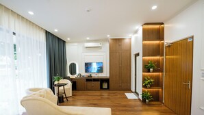 A hotel room with a bed, a sofa, a TV, a desk, and a wardrobe. - Azoma Hotel (Hanoi)