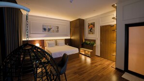 A modern bedroom with a bed, bedside table, chair, and a hanging chair. - Azoma Hotel (Hanoi)