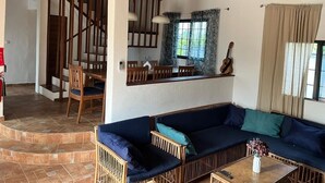 Un espace de vie comprenant un canapé, une table à manger, des chaises et un escalier.