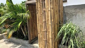 Une clôture en bambou avec une porte, entourée de plantes tropicales.