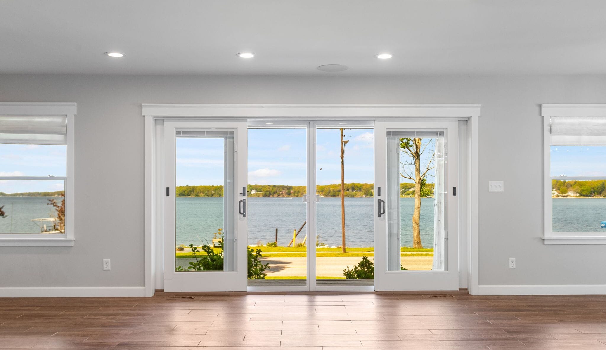 A spacious room with a large sliding glass door leading to a lakeside view.