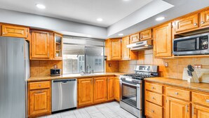 Une cuisine moderne avec des meubles en bois, des appareils électroménagers en acier inoxydable et un dosseret carrelé.