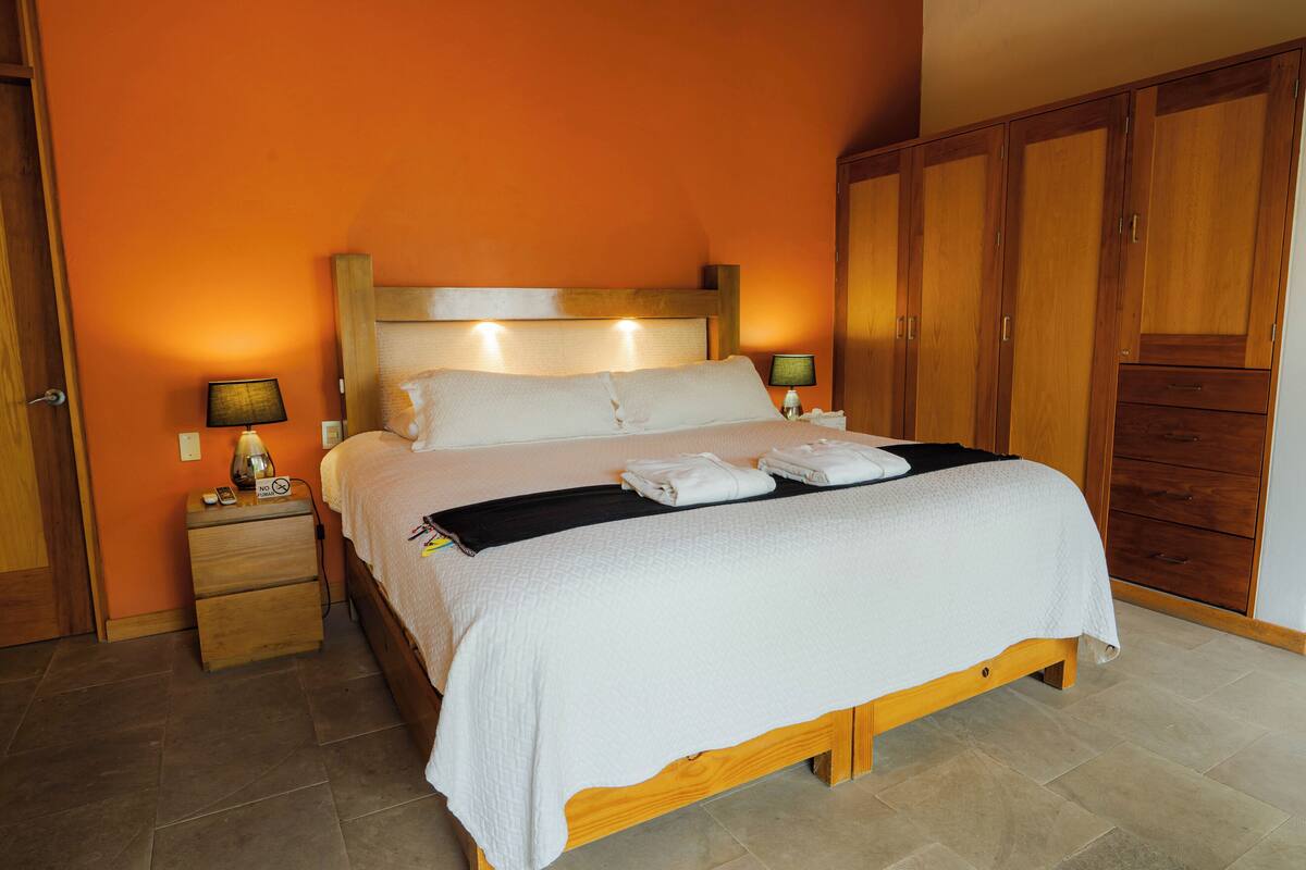 A neatly made bed with white linens and a black throw blanket, wooden headboard, and bedside lamps.