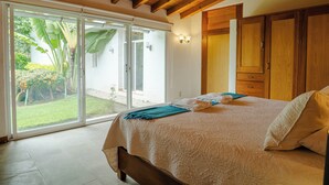 A bedroom with a bed, a sliding glass door to a garden, and wooden cabinets. - Finca Catalina Hotel Boutique  (Tepoztlán)