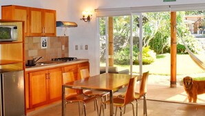 A kitchen with wooden cabinets, a microwave, and a dining area with a table and chairs. - Finca Catalina Hotel Boutique  (Tepoztlán)