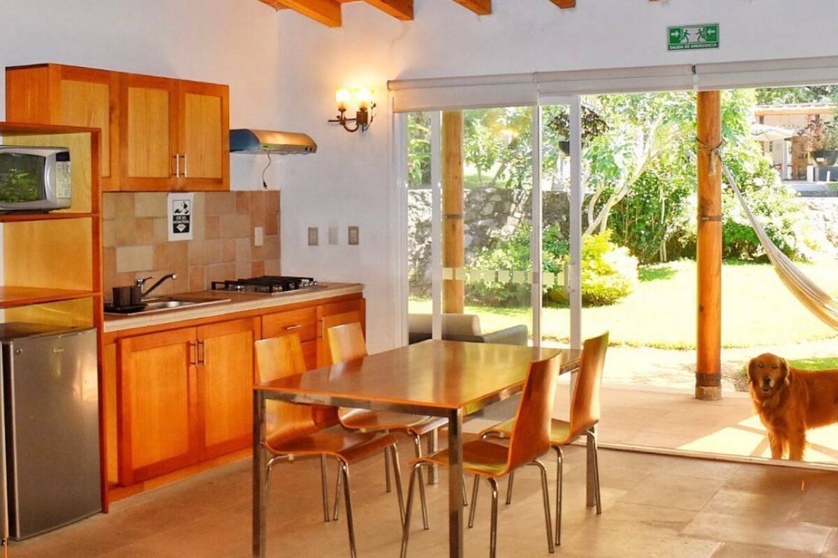 A kitchen with wooden cabinets, a microwave, and a dining area with a table and chairs.