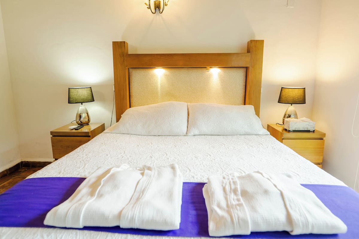A neatly made bed with white linens, two bedside lamps, and a wooden headboard.