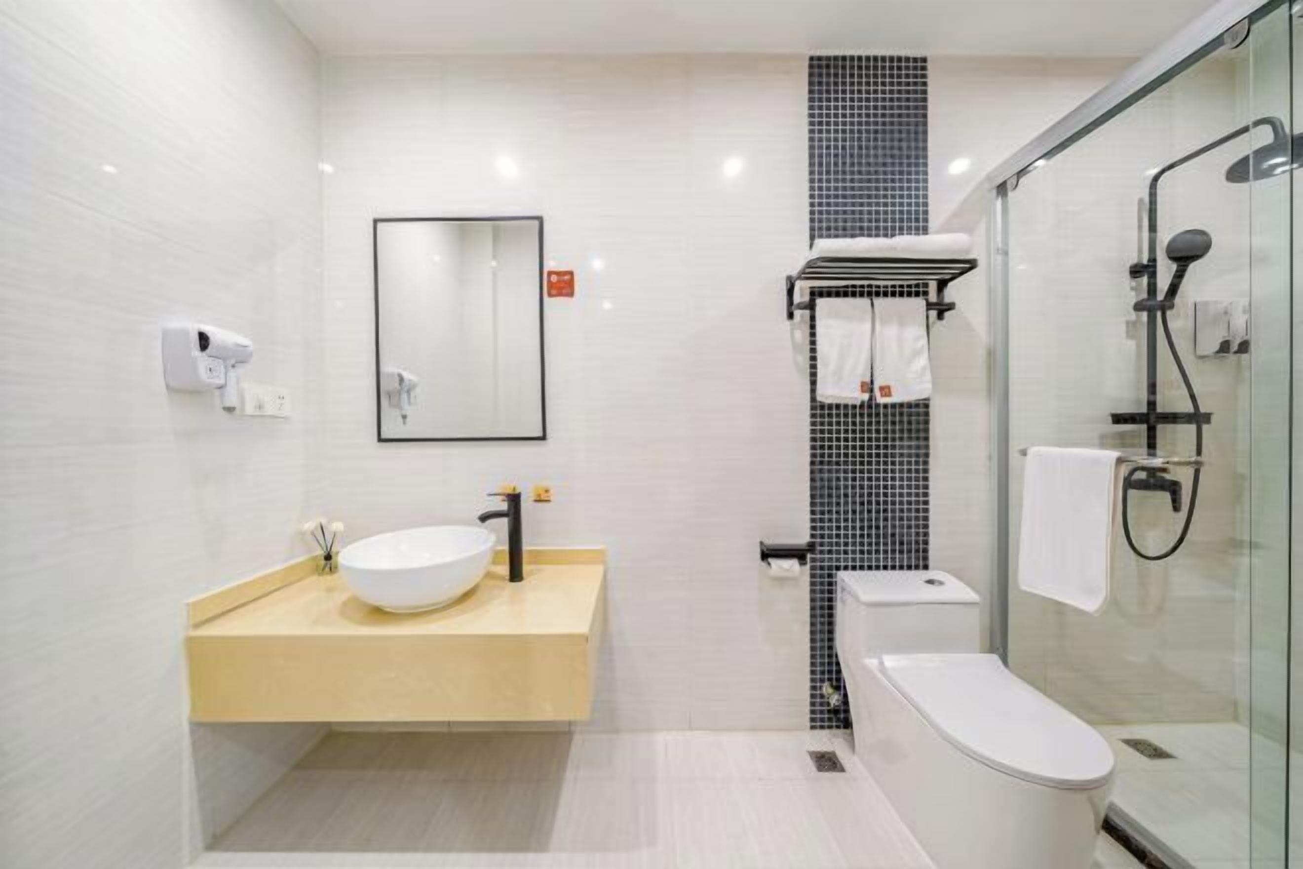 A modern bathroom with a white sink, black faucet, and a glass shower enclosure.
